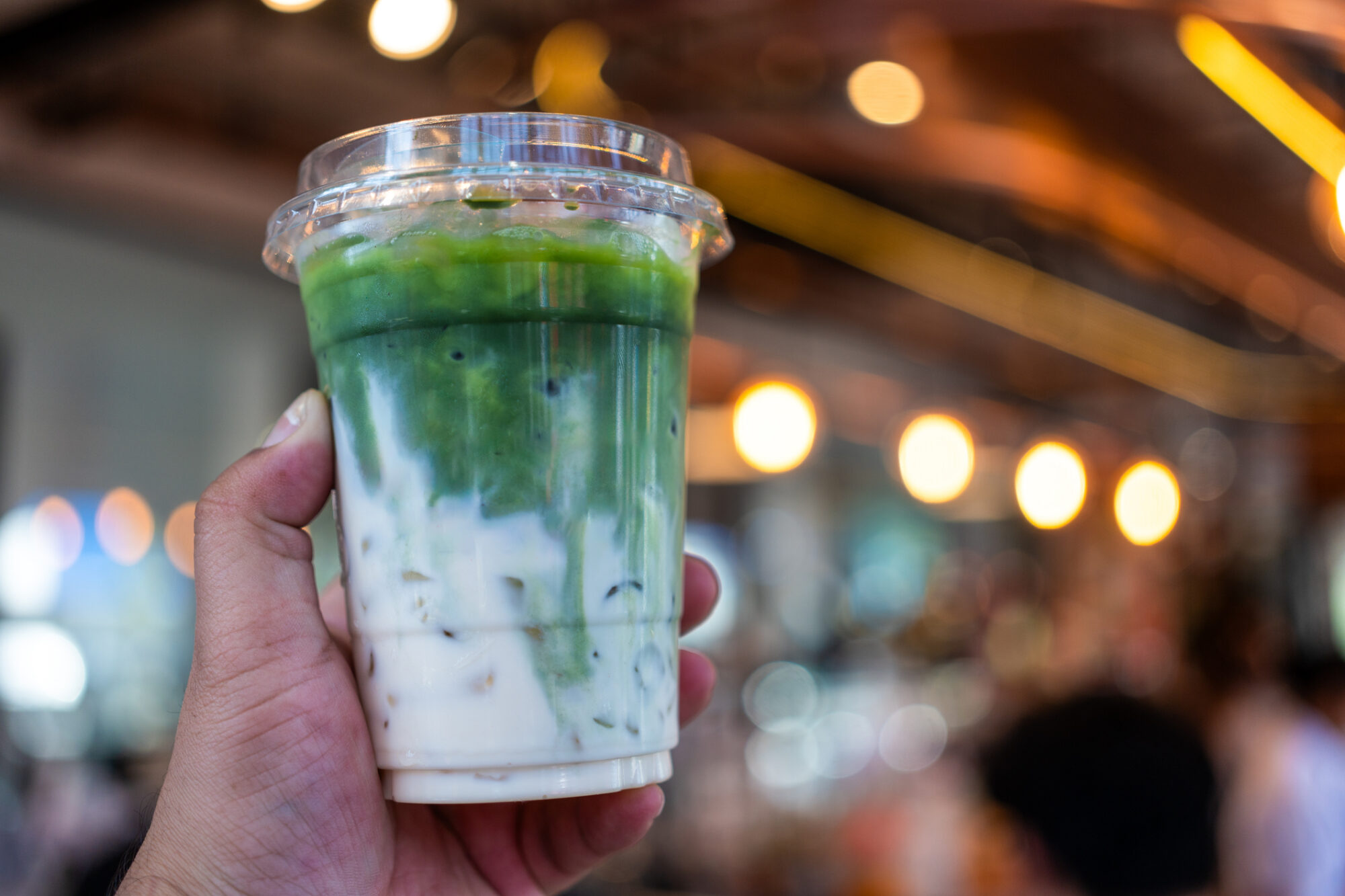 Hand holding iced matcha latte green tea